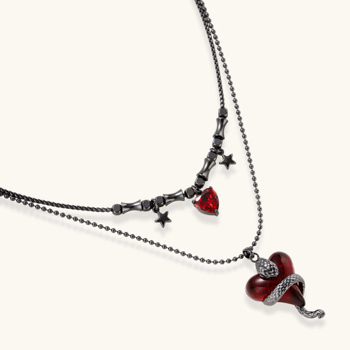 Dark layered necklace set with black chains and red heart pendants, featuring gothic snake design on white background