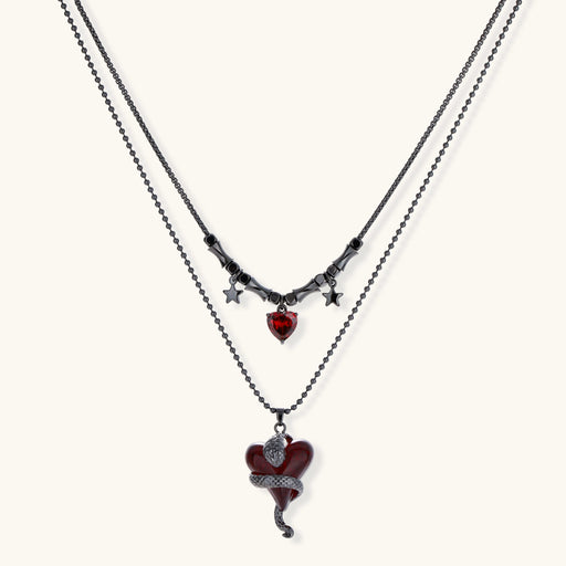 Dark layered necklace set with black chains and red heart pendants, featuring gothic snake design on white background