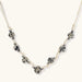 Adjustable cream cord necklace with white spotted stone beads featuring black speckles on neutral background