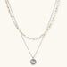 Two-layer necklace with natural stone chips and eco-brass beads, featuring a circular wrapped pendant on cream background.