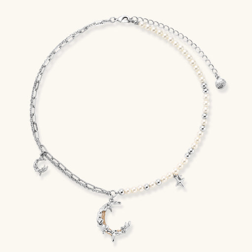 Silver-toned crescent moon pendant with star accents on pearl and chain necklace against white background.