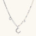 Silver-toned crescent moon pendant with star accents on pearl and chain necklace against white background.
