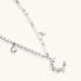 Silver-toned crescent moon pendant with star accents on pearl and chain necklace against white background.