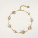 Gold-plated necklace with wire-wrapped shell pieces and freshwater pearls on neutral background, adjustable chain visible.