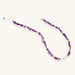 Beaded necklace with purple amethyst chips, freshwater pearls, and gold accents on white background.