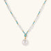 Beaded necklace with baroque pearls, turquoise stones, and gold accents featuring a large pearl pendant on white background.
