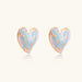 Heart-shaped stud earrings with swirled turquoise and pink enamel in gold-plated frames on cream background