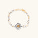 Stretchable bracelet with cream citrine stone chips, brass beads, and central amber zirconia pendant on neutral background.