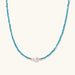 Delicate gold vermeil necklace with teal apatite beads and freshwater pearl on white background.