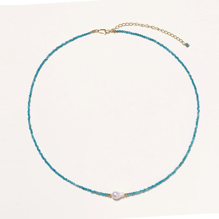 Delicate gold vermeil necklace with teal apatite beads and freshwater pearl on white background.