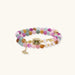 Stretchable bracelet with pastel gemstone beads, freshwater pearls, gold centerpiece and butterfly charm on cream background