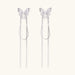 Pair of silver threader earrings with crystal butterfly tops and long chain drops on cream background.