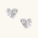 Pair of sculptural white gold-plated stud earrings with twisted ribbon design and sparkling zirconia stones on cream background