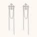 White gold plated baroque cross stud earrings with long cascading zirconia chains on cream background