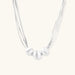 Sterling silver multi-strand necklace with three brushed round beads on cream background