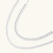 Long sterling silver beaded necklace with graduated sphere design, toggle clasp, and delicate chain extension on white background