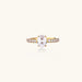 Gold-plated solitaire ring with oval zirconia center stone and pavé band on cream background