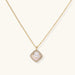 Gold quatrefoil pendant with crystal center on iridescent mother-of-pearl base, adjustable gold chain on cream background