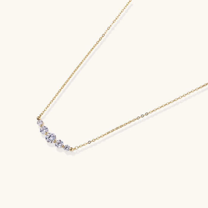 Delicate 14K gold-plated necklace with five graduated zirconia stones arranged in a curved arc on fine chain
