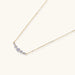 Delicate 14K gold-plated necklace with five graduated zirconia stones arranged in a curved arc on fine chain