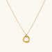 Delicate gold-plated necklace with three interlocking circle rings forming a minimalist knot pendant on cream background