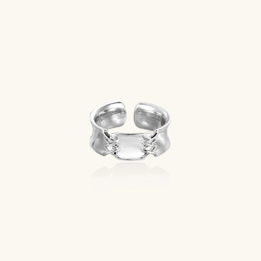 Adjustable silver-toned ring with sculptural stitch design across polished white gold-plated brass band