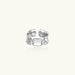 Adjustable silver-toned ring with sculptural stitch design across polished white gold-plated brass band
