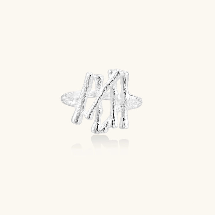 Sculptural sterling silver ring with organic branch design and textured surfaces on cream background